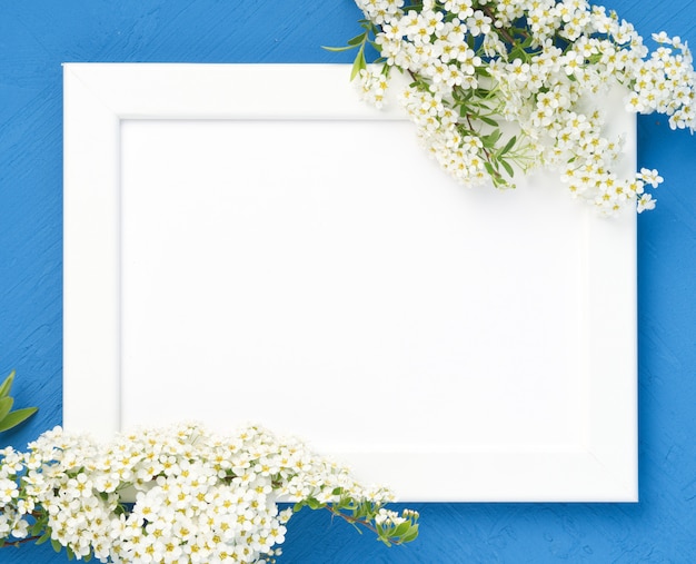 Fleurs blanches sur le cadre sur fond de béton bleu foncé.
