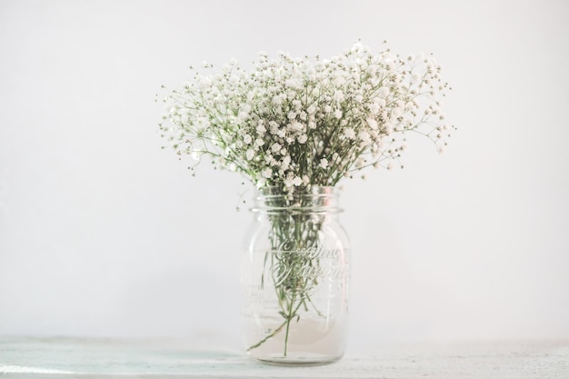 Fleurs blanches dans un vase sur un bureau en bois