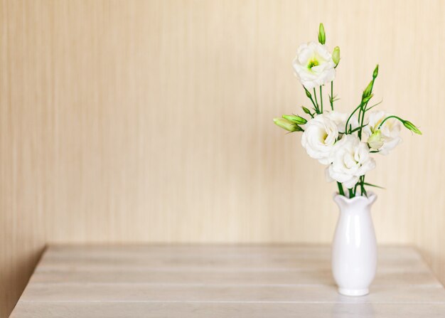 Fleurs blanches Eustoma ou Lisianthus dans un vase sur une table en bois avec espace de copie.