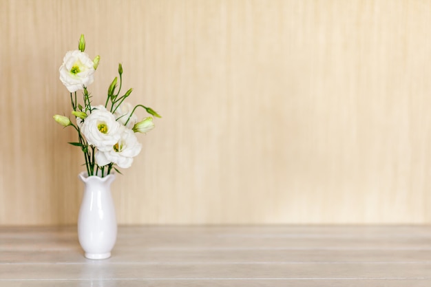 Fleurs blanches Eustoma ou Lisianthus dans un vase sur une table en bois avec espace de copie.