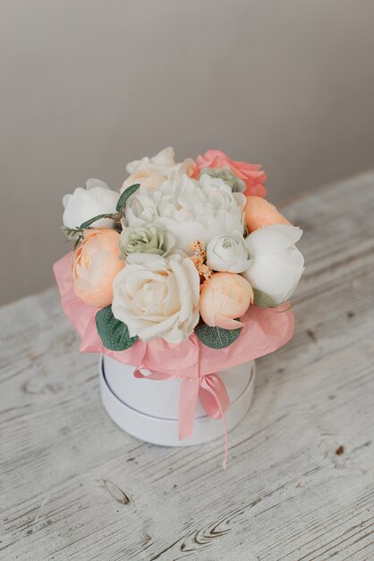 Fleurs blanches et roses dans une boîte cadeau. Fleurs décoratives. Fleurs artificielles dans une boîte ronde.