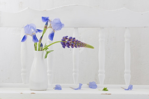 Fleurs bleues dans un vase sur une étagère en bois blanc