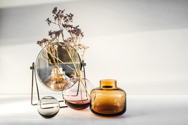 Fleurs de branche dans un vase en verre et miroir sur table blanche. Décor pour l'intérieur. Décoration élégante pour la maison.