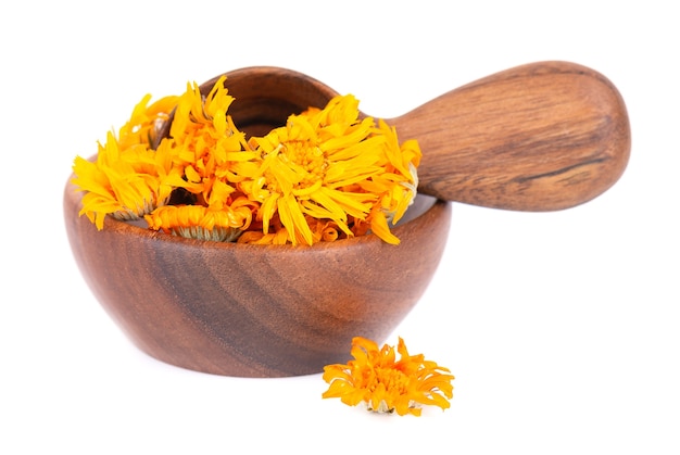 Fleurs de calendula séchées dans un bol en bois et une cuillère isolés sur fond blanc pétales de calendula