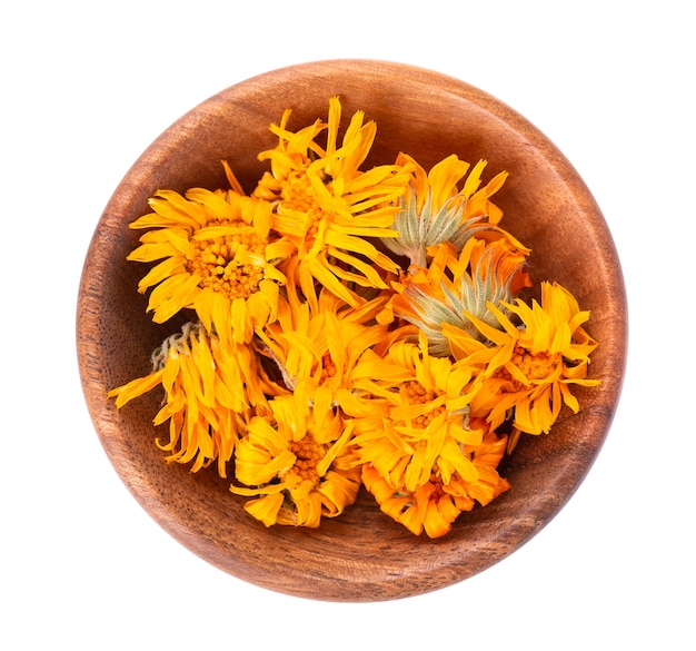 Fleurs de calendula séchées dans un bol en bois, isolés sur fond blanc. Pétales de Calendula officinalis. Herbes medicinales. Vue de dessus.