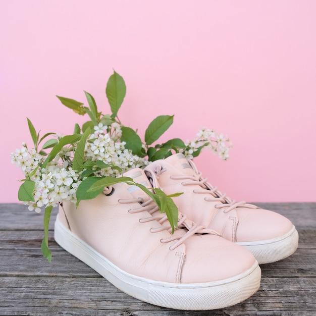 Fleurs de cerisier en baskets roses sur fond rose.