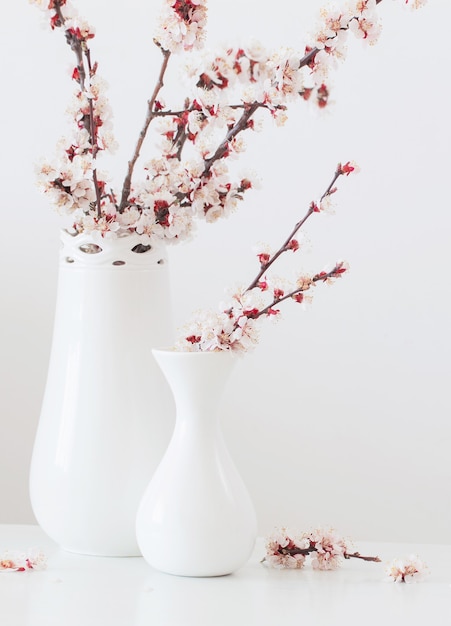 Fleurs de cerisier dans un vase avec des bougies roses sur fond blanc