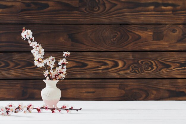 Fleurs de cerisier dans un vase sur une surface en bois