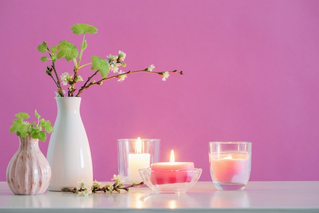 Fleurs de cerisier de printemps et bougies sur mur rose