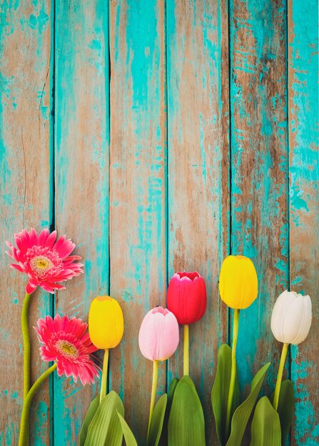 Photo fleurs colorées sur fond en bois vintage, vue de dessus