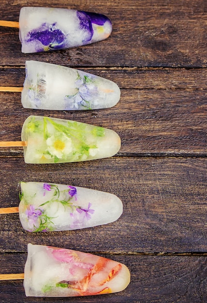 Fleurs congelées dans des glaçons et de la crème glacée sur un bâton. mise au point sélective.