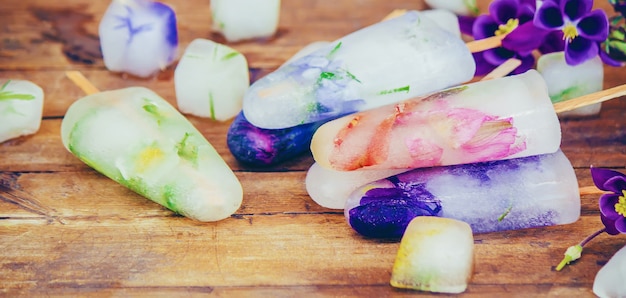 Fleurs congelées dans des glaçons et de la crème glacée sur un bâton. mise au point sélective.