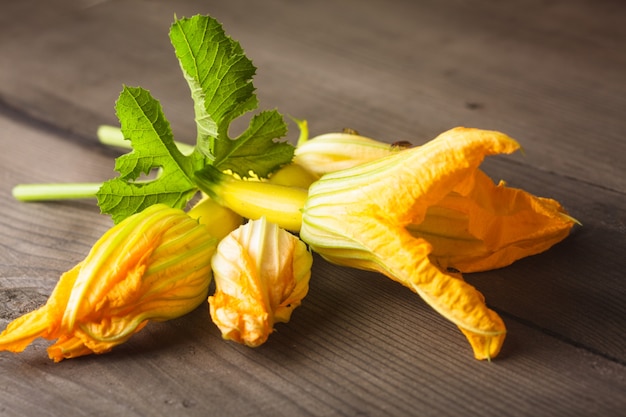 Fleurs de courgettes sur une table en bois se bouchent