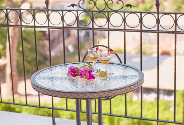 Fleurs créatives d'été et boissons maison sur table en verre en journée d'été ensoleillée sur le balcon