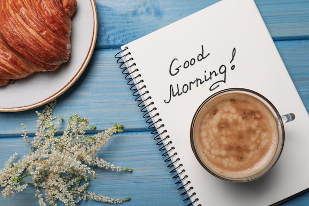 Fleurs de croissant de café aromatique et message de bon matin sur une table en bois bleu clair à plat