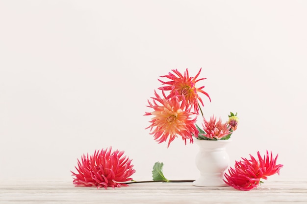 Fleurs de Dahlia dans un vase blanc sur une table en bois