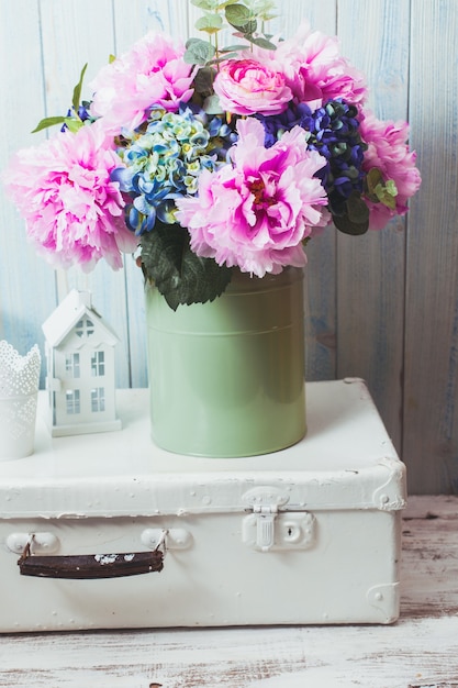 Fleurs dans une boîte vintage bleue sur sac rétro blanc et faïence de cuisine