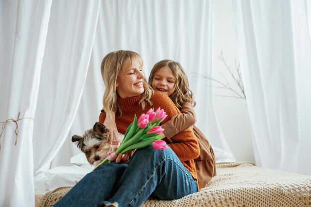 Des fleurs dans les mains Le concept de la fête des mères La mère avec sa fille est à la maison