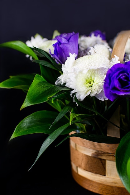 Fleurs dans un panier. Roses dans un panier. Cadeau. Les fleurs sont blanches et violettes.