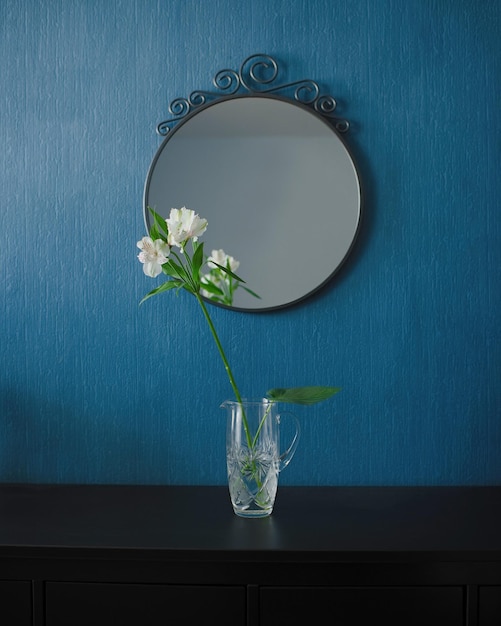 Fleurs dans un vase sur une commode noire, miroir