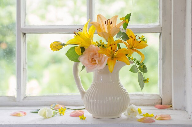 Fleurs dans un vase sur le rebord de la fenêtre