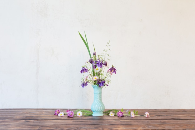 Fleurs dans un vase sur une table en bois sur fond blanc mur