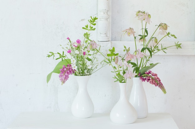 Fleurs dans des vases sur fond blanc