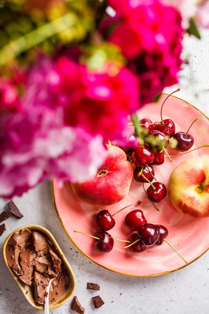 Fleurs, dessert au chocolat et baies sur une plaque rose.