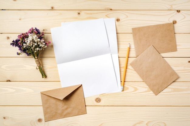 Des fleurs, du papier blanc et une enveloppe sur une table.