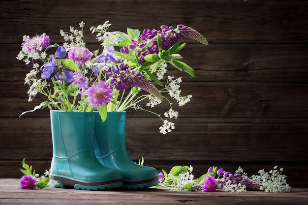 Photo fleurs d'été dans des bottes en caoutchouc sur de vieux bois foncé