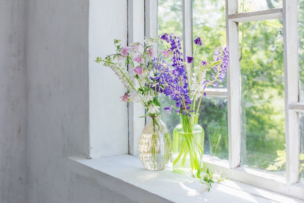 Fleurs d'été dans un vase sur le rebord de la fenêtre au soleil