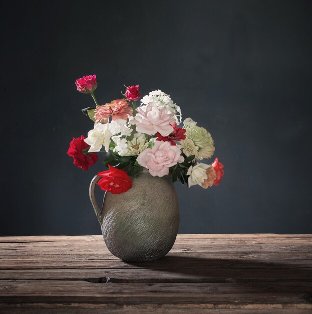 Fleurs d'été en pot en céramique sur table en bois sur fond sombre