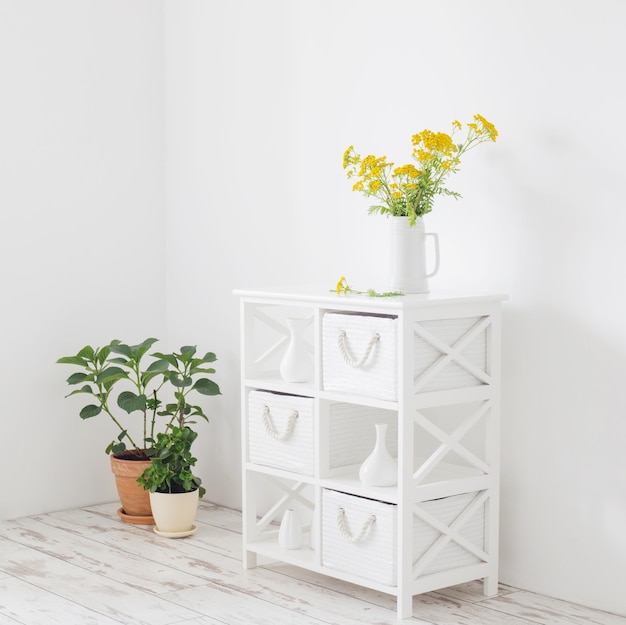 fleurs d'été sauvages jaunes dans une cruche sur un intérieur vintage blanc