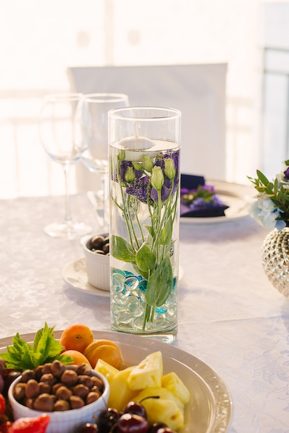 Fleurs d'eustoma pourpre dans un vase en verre avec de l'eau sur la table de fête au mariage, décoration de mariage