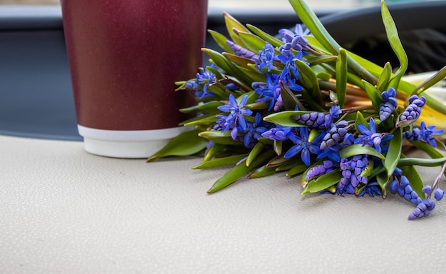 fleurs de forêt violette dans un intérieur de voiture moderne le printemps arrive eco coffee tasse en carton à côté de f