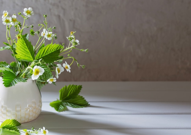 Fleurs de fraise dans un vase sur fond ancien