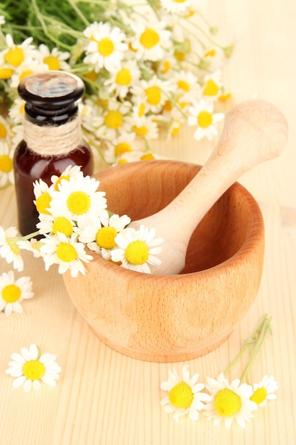 Fleurs d'huile essentielle et de camomille dans un mortier sur une table en bois