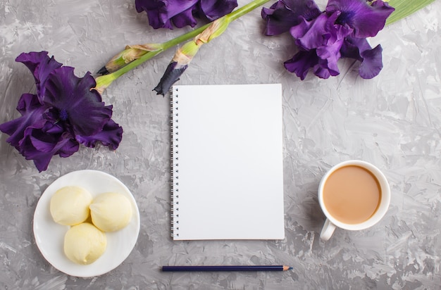 Fleurs d&#39;iris pourpres et une tasse de café avec guimauve et cahier sur béton gris