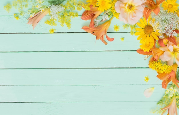 Fleurs jaunes et orange sur une surface en bois verte