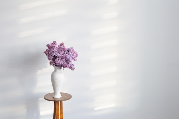 Fleurs lilas dans un vase blanc sur fond de mur blanc