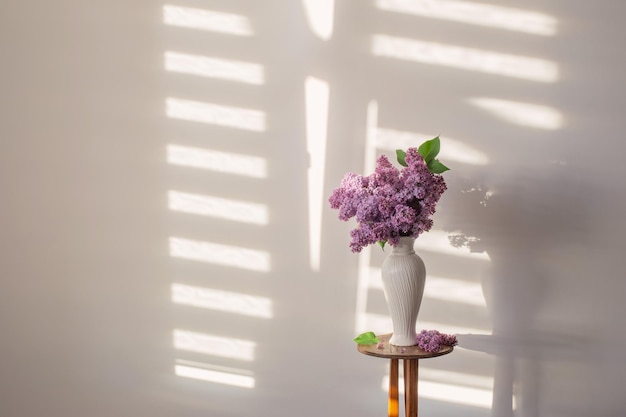 Fleurs lilas dans un vase blanc sur fond de mur blanc