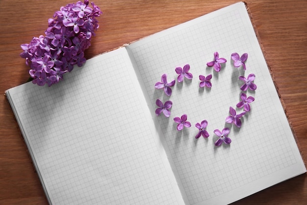 Fleurs lilas en forme de coeur sur un livre blanc ouvert