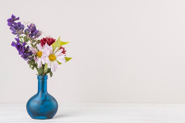 Fleurs lumineuses dans un vase bleu sur la table