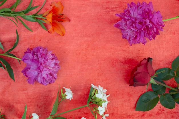 Fleurs lumineuses sur textiles rougesContexte avec des fleurs Vue d'en haut Contexte festif Journée internationale de la femme Saint Valentin