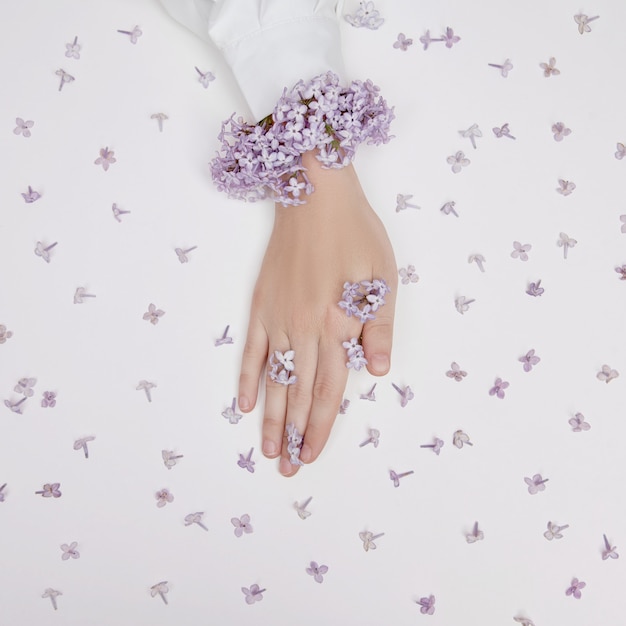 Fleurs de lys de printemps dans les mains d'une femme allongée sur une table blanche. Cosmétiques naturels pour les mains, mains anti-rides. Beauté naturelle d'une femme