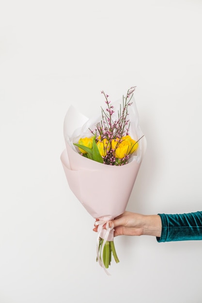 Des fleurs en main féminine sur blanc