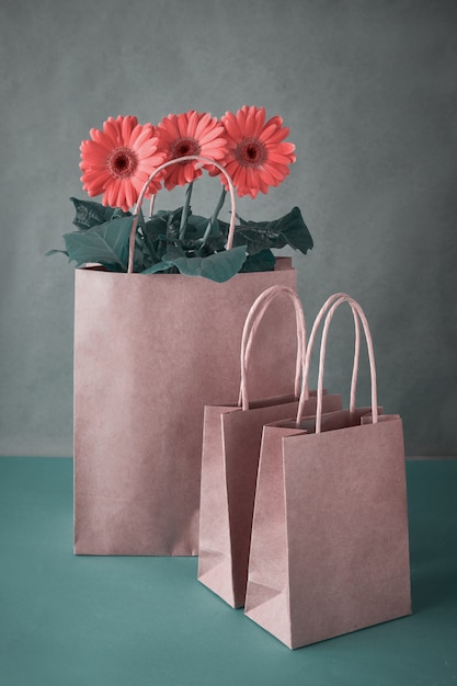 Fleurs de marguerite gerbera corail et sacs à provisions artisanaux sur papier