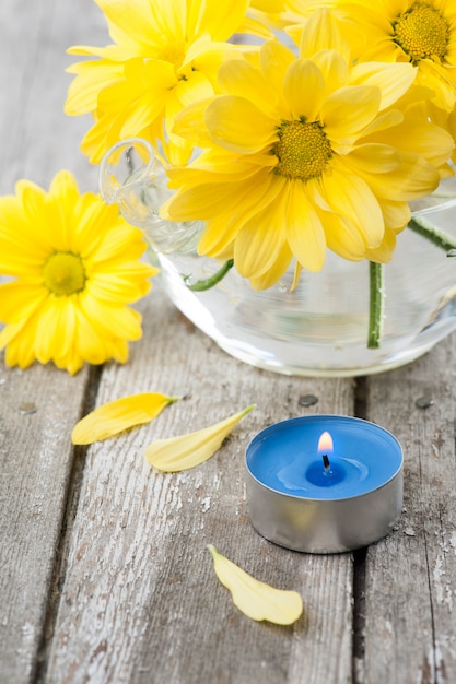 Fleurs de marguerite jaune fraîche et bougie allumée bleue