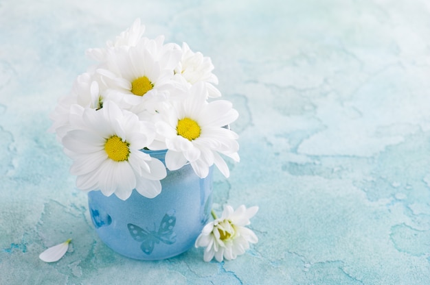 Fleurs de marguerites fraîches en verre bleu