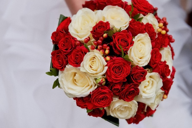 Fleurs de mariage un bouquet de roses rouges et crème avec des baies rougesLe bouquet de la mariée